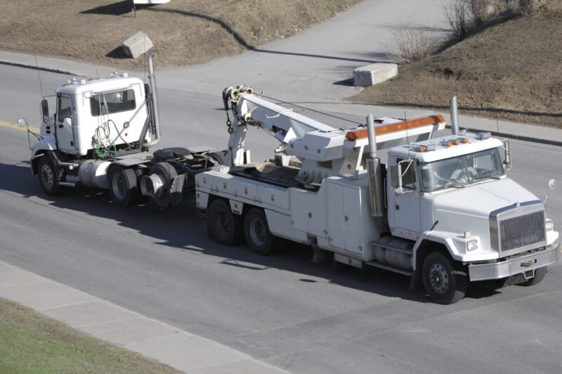 Big semi truck tow by heavy tow truck.