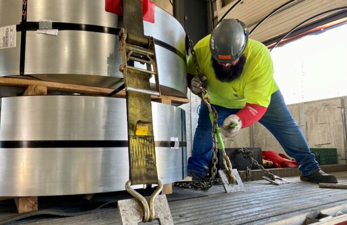Picture of a driver securing a steel load.