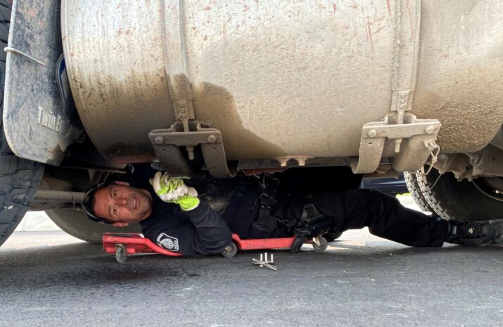 Picture of a leaking fuel tank and officer under truck