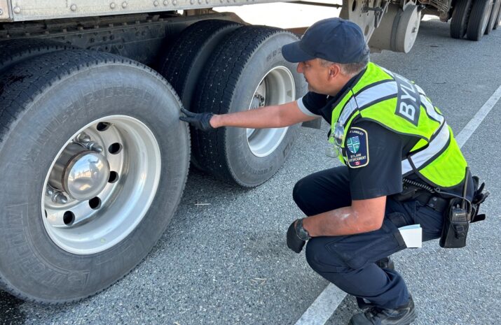 Bylaw officer inspecting a truck's tire