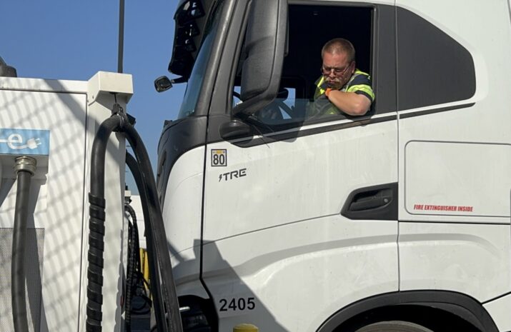 driver parking in Nikola EV truck near a charger
