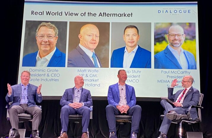 Four men sitting on chairs on a stage