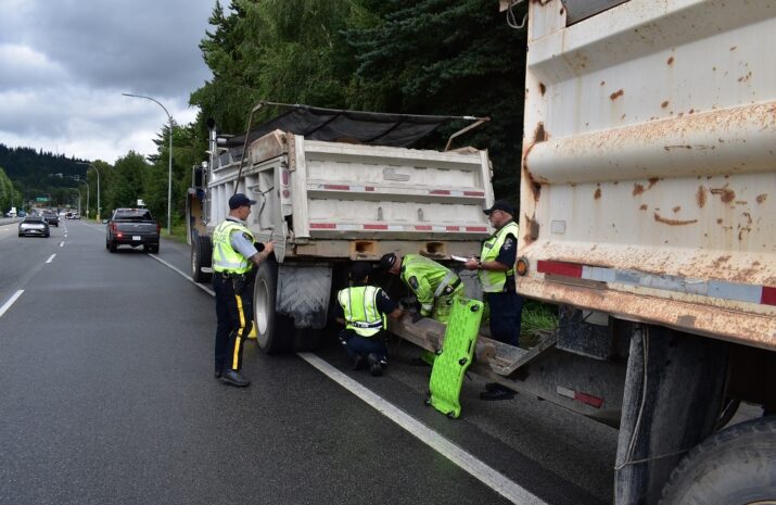 Officers inspect a dump truck and trailer