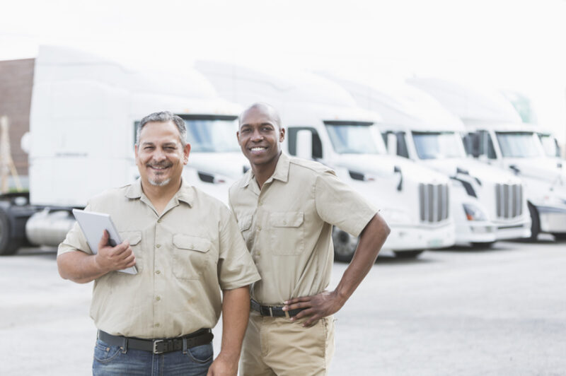 Two men standing in front of trucks