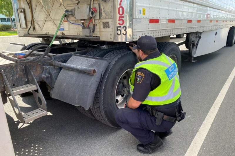 An MTO officer inspects a tire