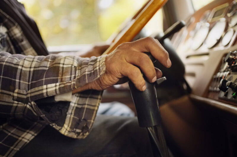 Close-up of man driving farming tractor with hands on the gear lever and steering wheel