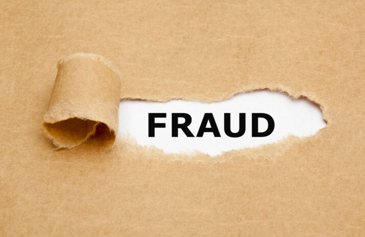 The word Fraud appearing behind torn brown paper.