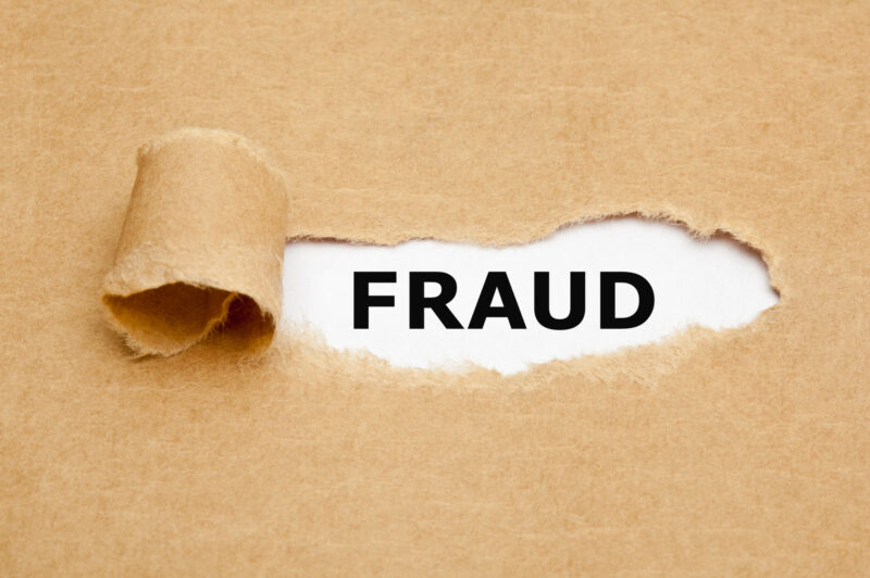 The word Fraud appearing behind torn brown paper.